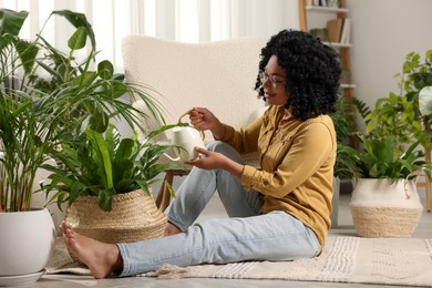 Photo of Woman watering beautiful potted houseplant at home