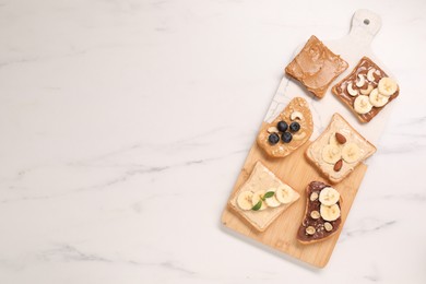 Photo of Toasts with different nut butters, fruits and nuts on white marble table, flat lay. Space for text