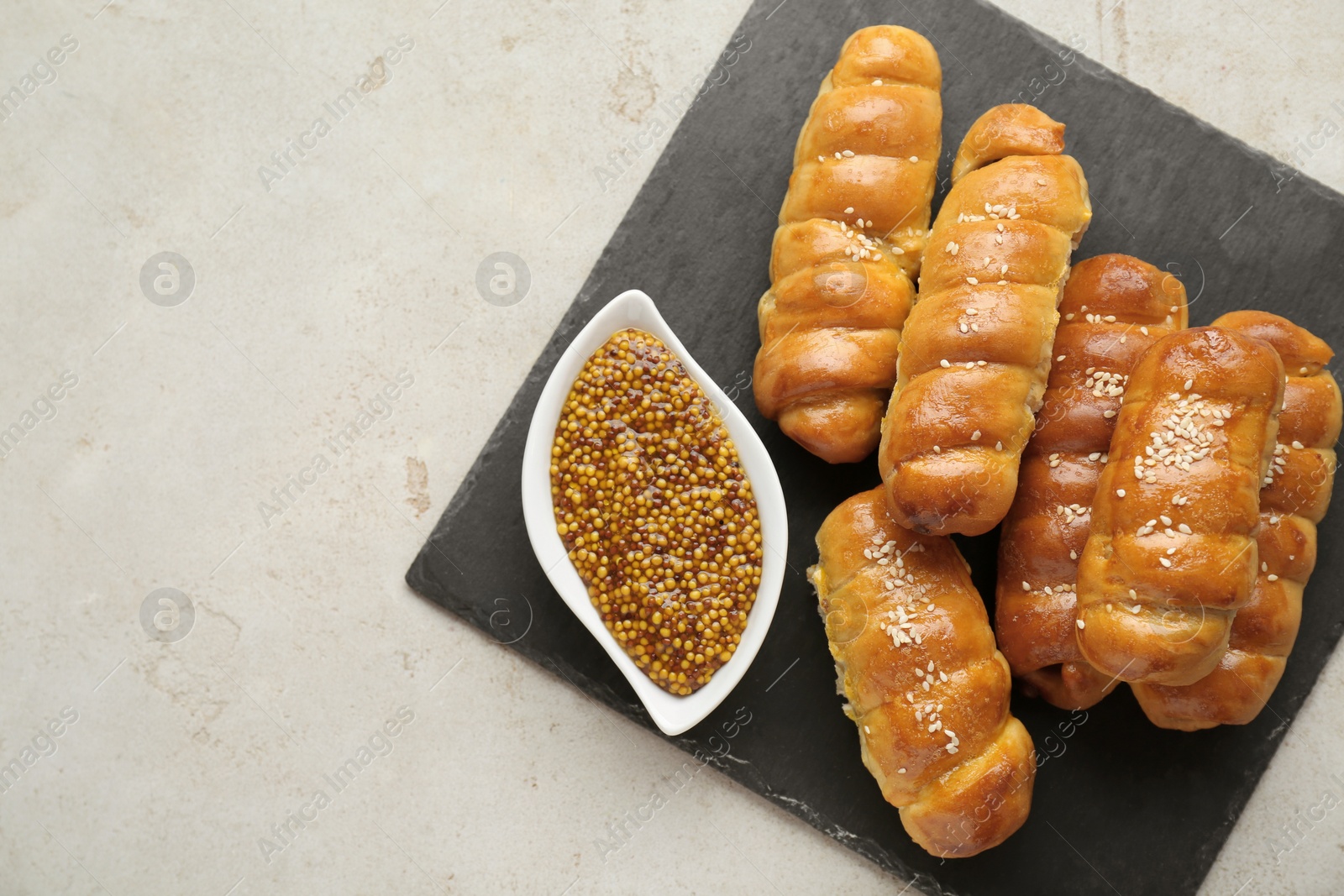 Photo of Delicious sausage rolls and grain mustard on beige table, top view. Space for text