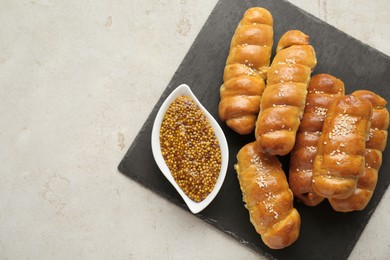 Delicious sausage rolls and grain mustard on beige table, top view. Space for text