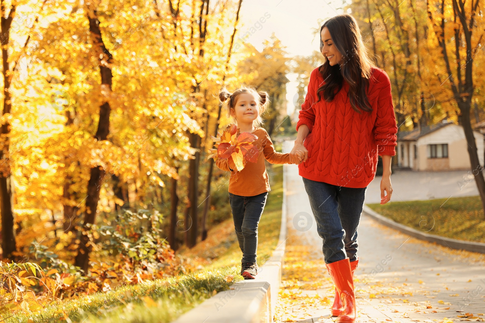 Photo of Happy woman with daughter walking in sunny autumn park