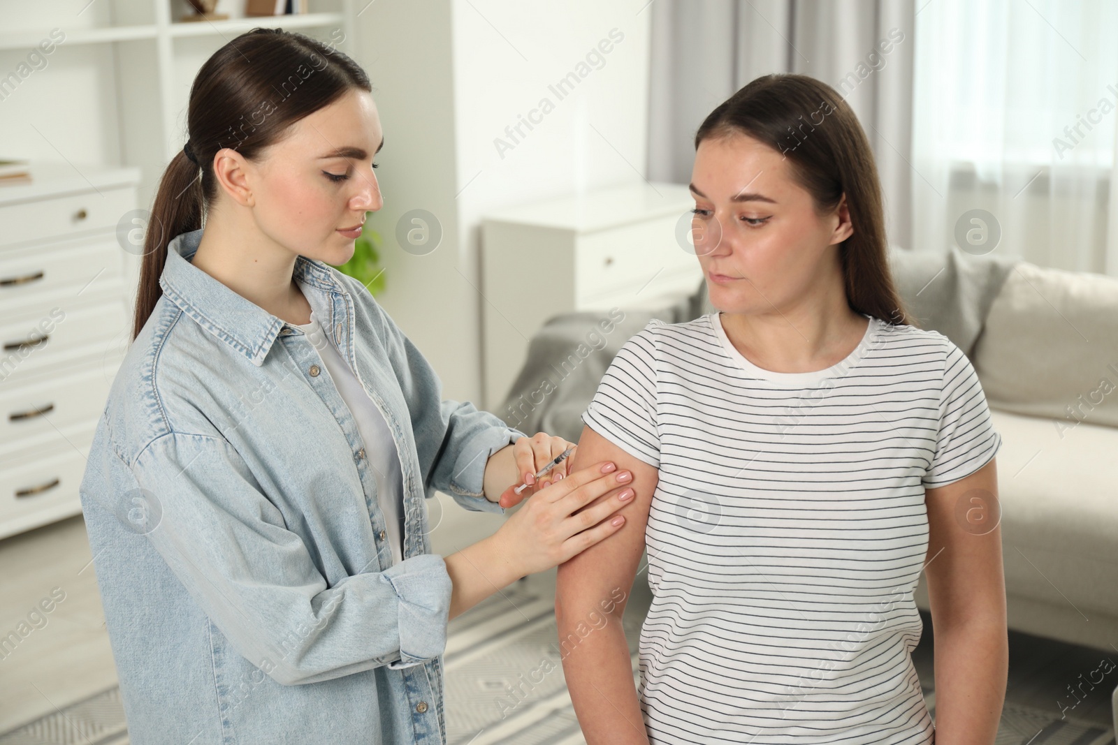 Photo of Woman giving insulin injection to her diabetic friend at home