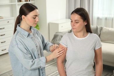 Photo of Woman giving insulin injection to her diabetic friend at home