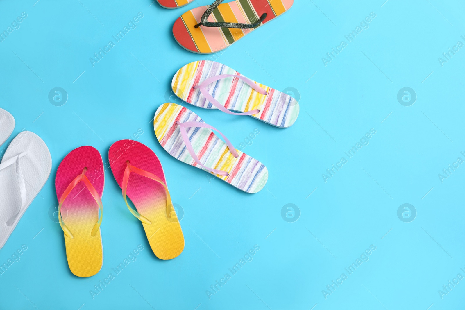 Photo of Flat lay composition with different flip flops on blue background, space for text. Summer beach accessories