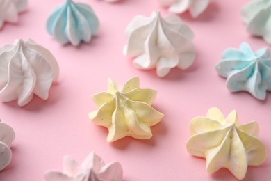 Many tasty meringue cookies on pink background, closeup