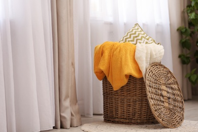 Basket with blankets and pillow near window indoors