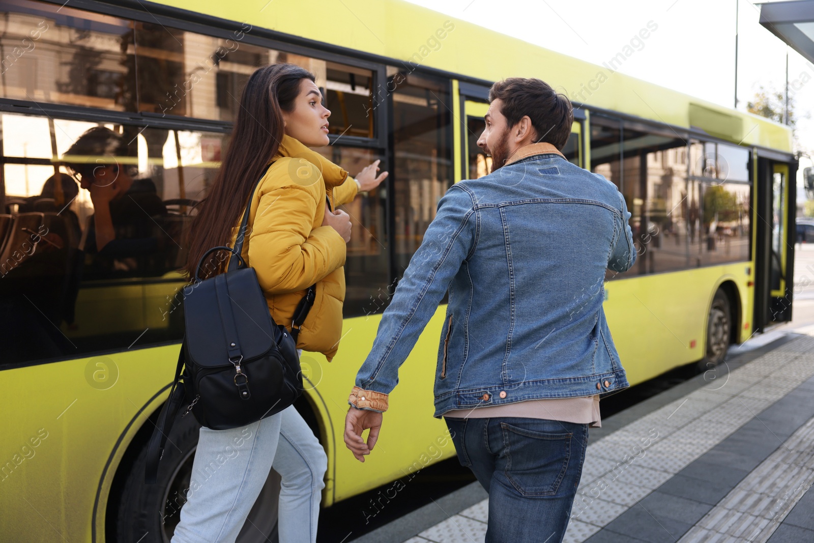 Photo of Being late. Worried couple running towards bus outdoors