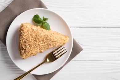 Piece of delicious Napoleon cake served on white wooden table, top view. Space for text