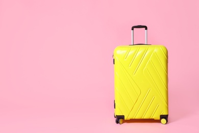 Photo of Modern yellow suitcase on light pink background. Space for text