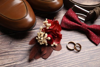 Photo of Wedding stuff. Composition with stylish boutonniere on wooden background, closeup