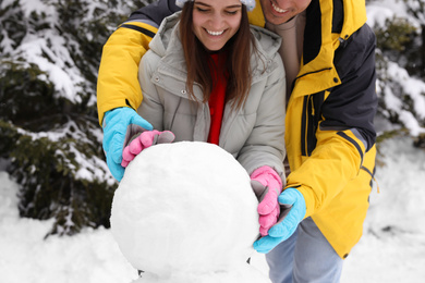 Happy couple making snowman outdoors, closeup. Winter vacation