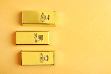Shiny gold bars on pale orange background, flat lay. Space for text