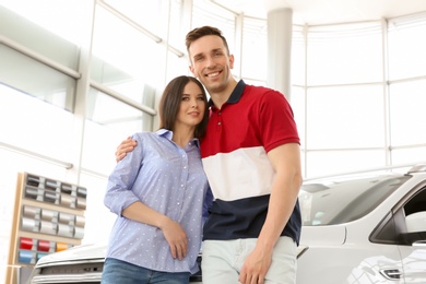 Young couple near auto in salon. Buying new car