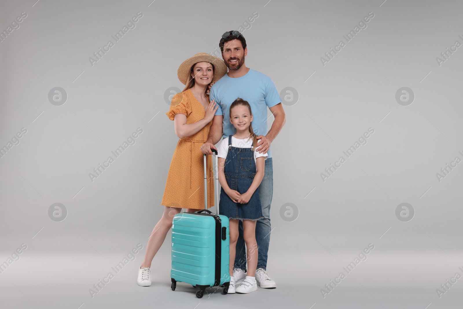Photo of Happy family with turquoise suitcase on light grey background