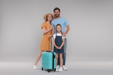 Happy family with turquoise suitcase on light grey background