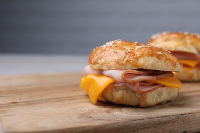 Photo of Delicious bagels with ham and cheese on wooden table, closeup. Space for text