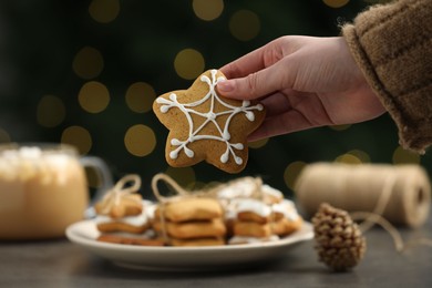 Photo of Woman with decorated Christmas cookie at table, closeup