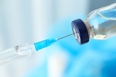 Filling syringe with vaccine on blurred background, closeup