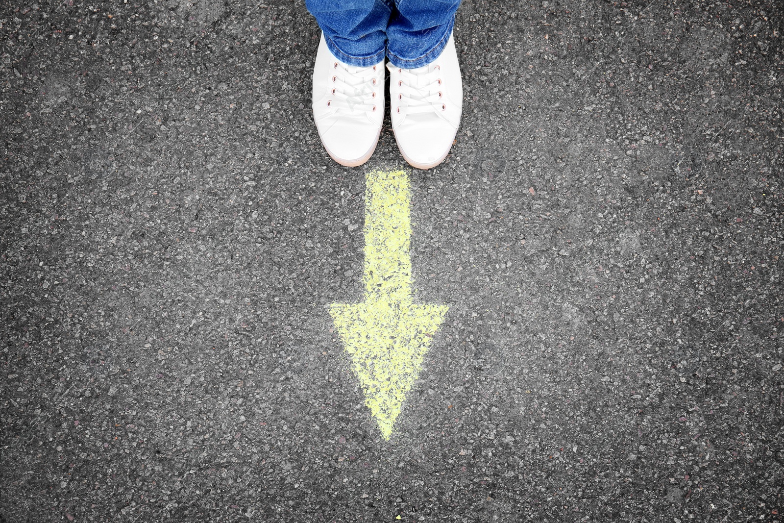 Photo of Woman standing on road near arrow marking, closeup