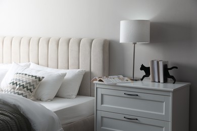 Photo of Stylish lamp, books and magazine on bedside table indoors. Bedroom interior elements