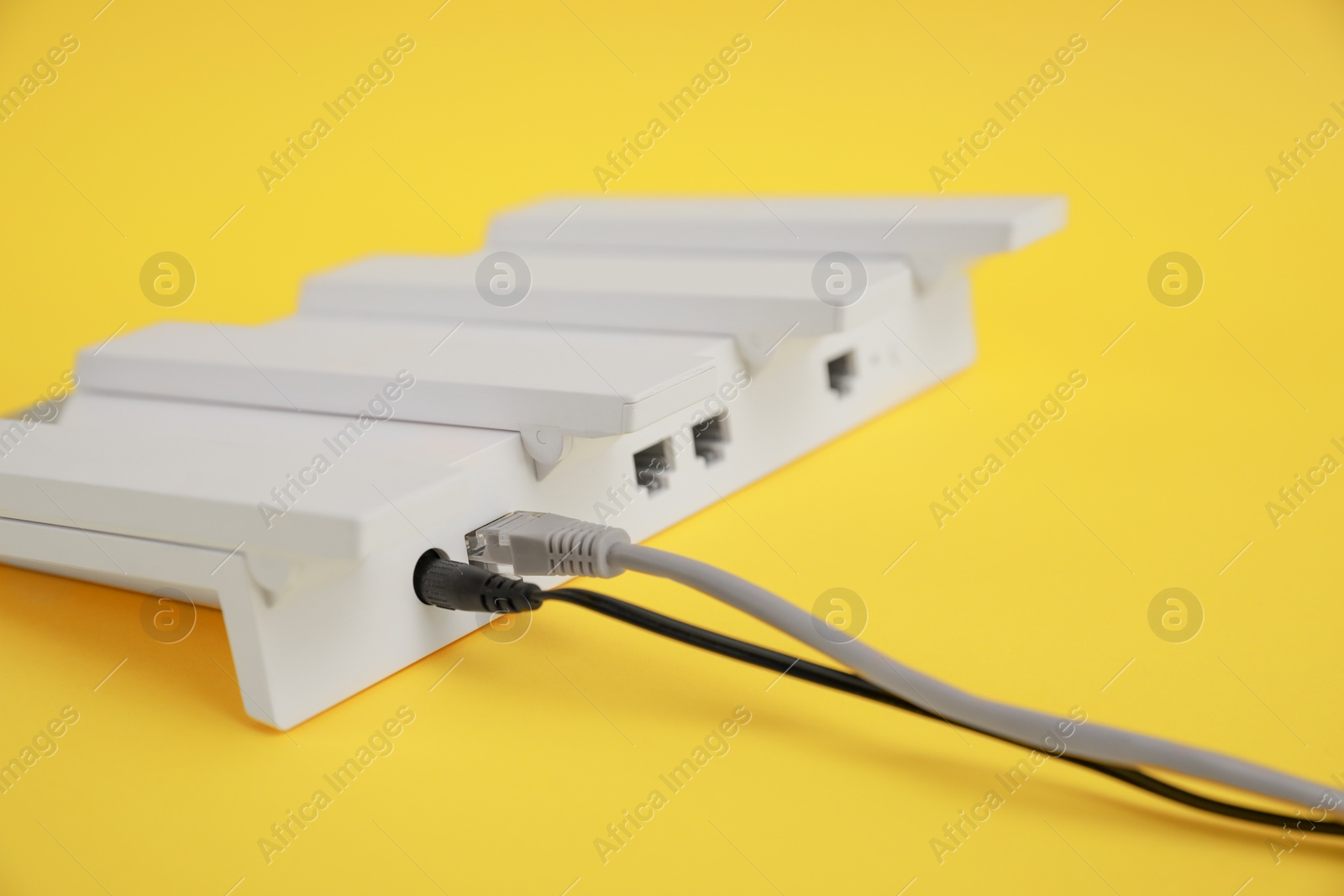 Photo of Modern Wi-Fi router on yellow background, closeup