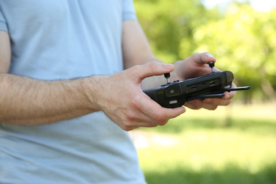 Man holding new modern drone controller outdoors, closeup of hands