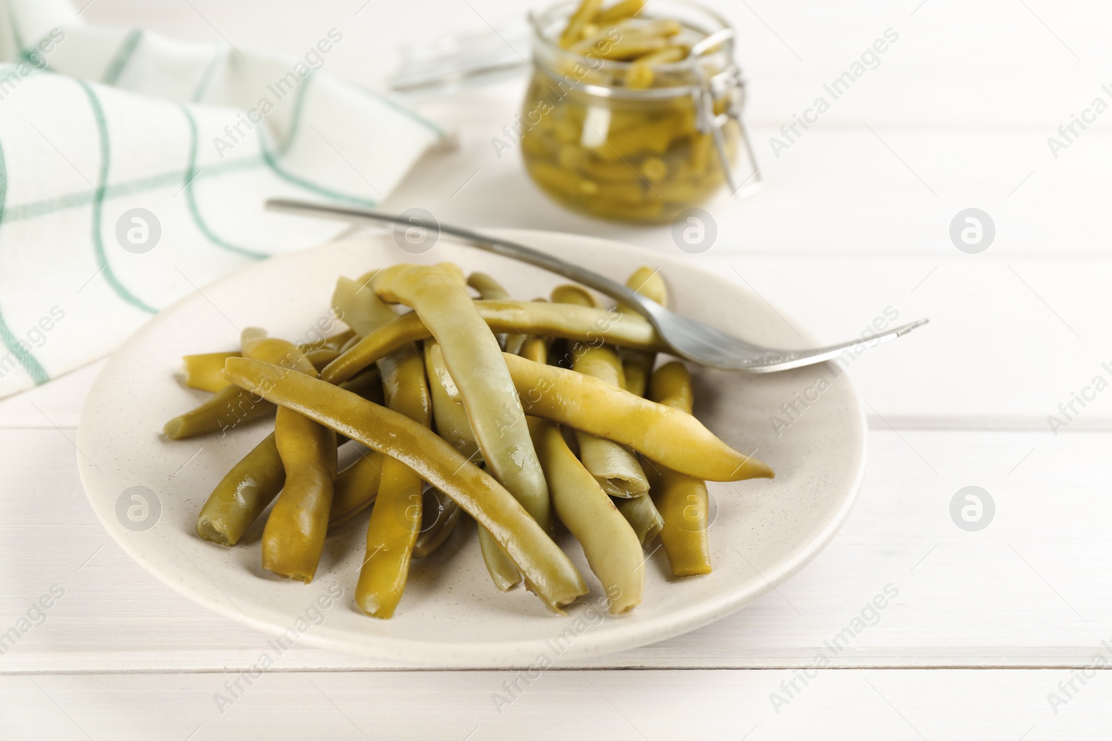 Photo of Canned green beans on white wooden table, closeup