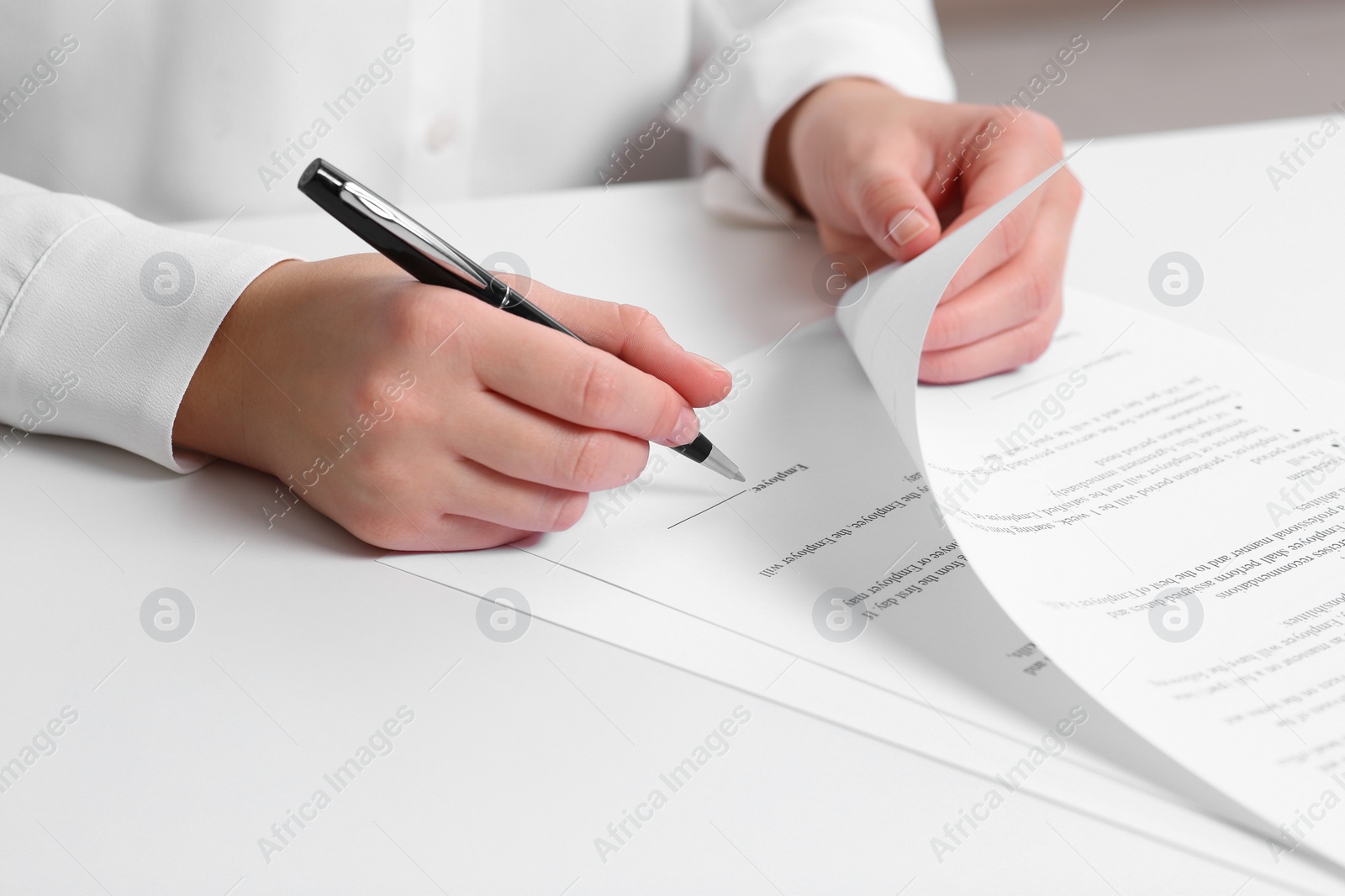 Photo of Businesswoman signing contract at white table, closeup of hands