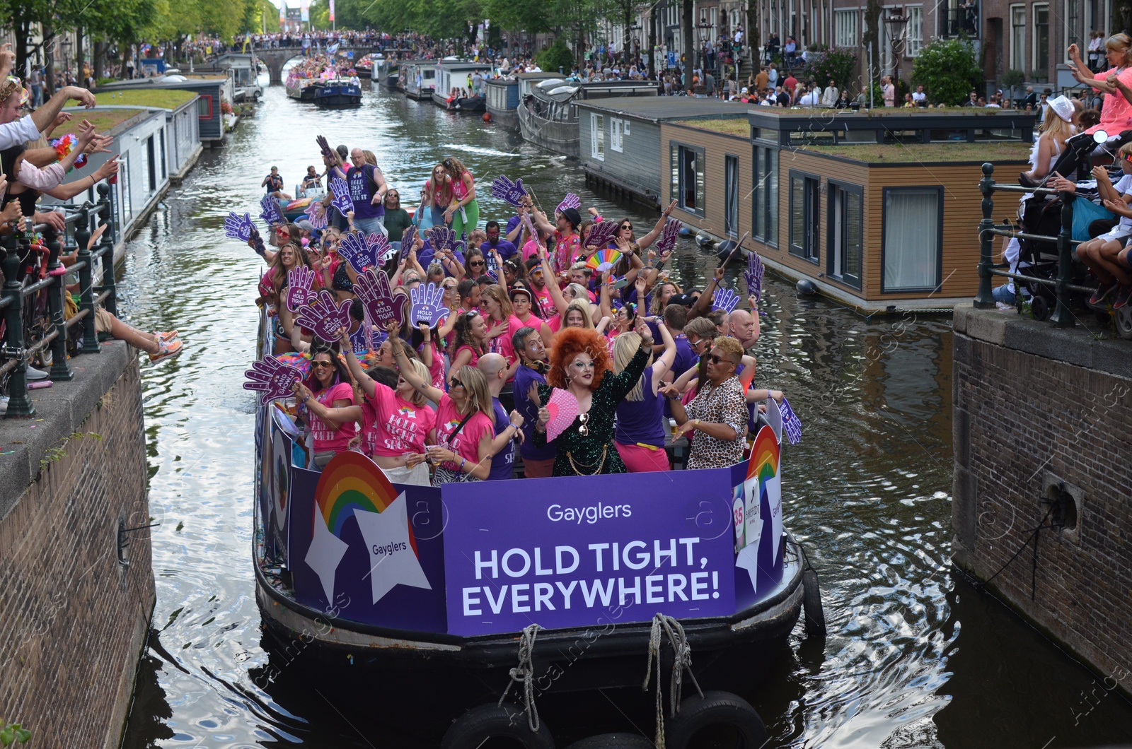 Photo of AMSTERDAM, NETHERLANDS - AUGUST 06, 2022: Many people in boats at LGBT pride parade on river