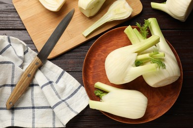 Fresh raw fennel bulbs and knife on wooden table, flat lay