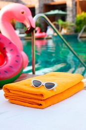 Beach towels and sunglasses on sun lounger near outdoor swimming pool. Luxury resort