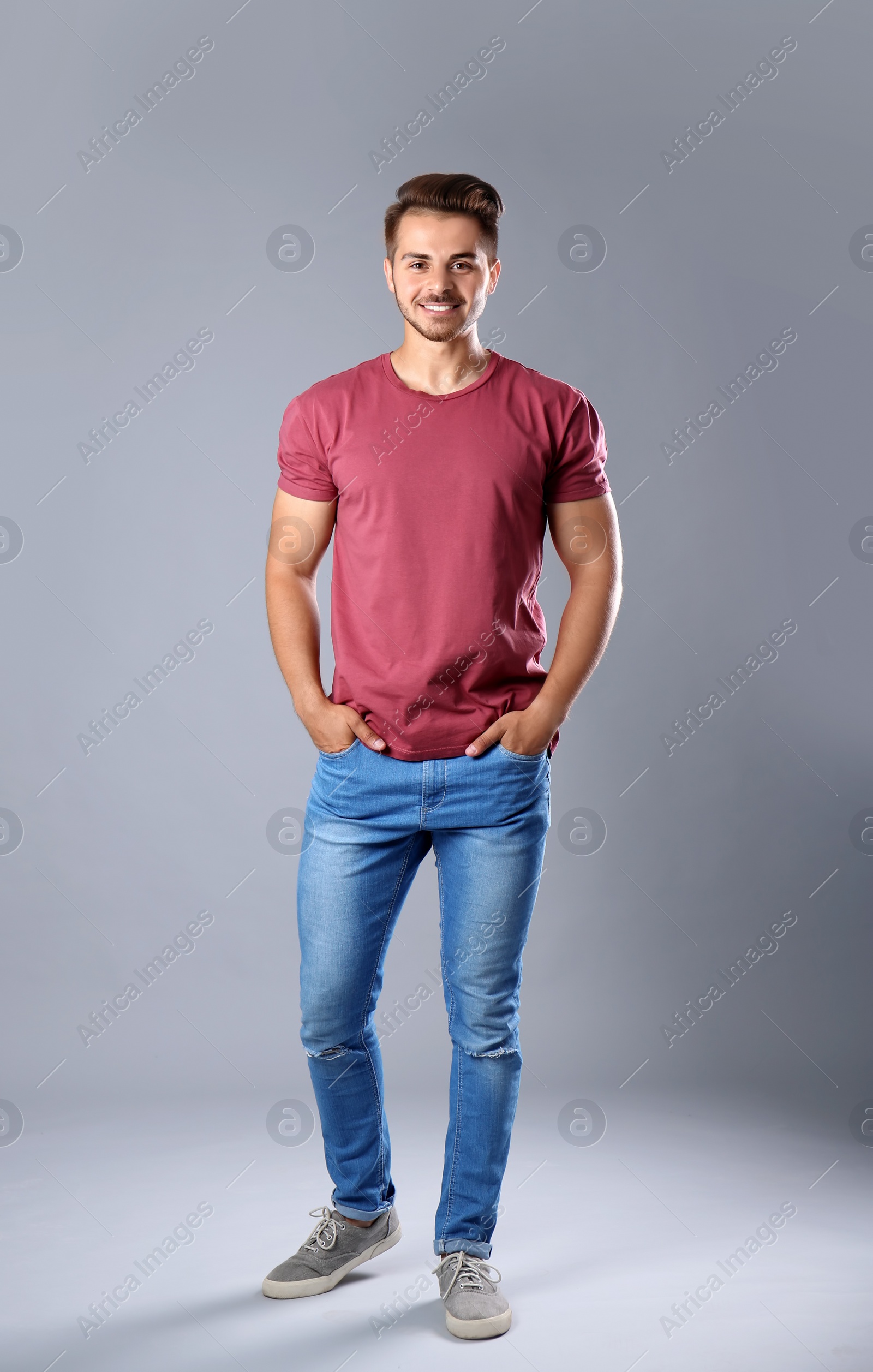 Photo of Young man in stylish jeans on grey background