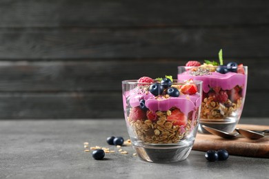 Tasty dessert with acai smoothie, granola and berries on grey table. Space for text