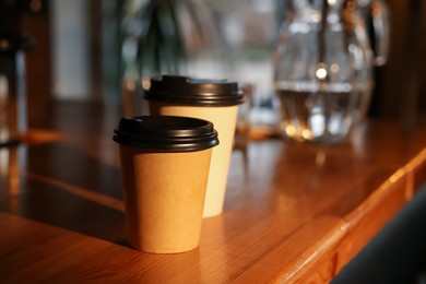 Photo of Paper coffee cups on wooden table in cafe