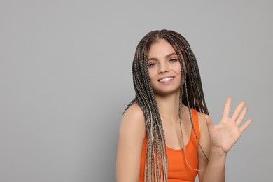 Young woman giving high five on grey background, space for text