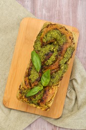 Photo of Freshly baked pesto bread with basil on wooden table, top view