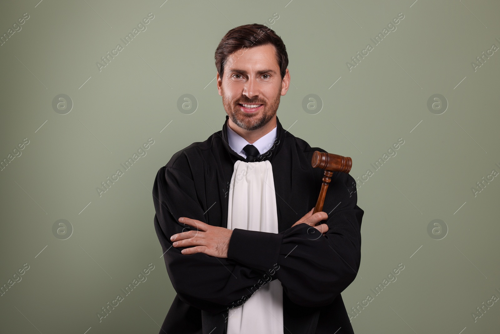 Photo of Happy judge with gavel on green background