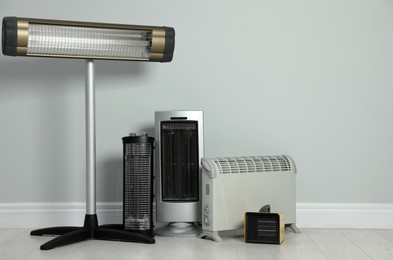 Photo of Different electric heaters near light grey wall indoors. Space for text