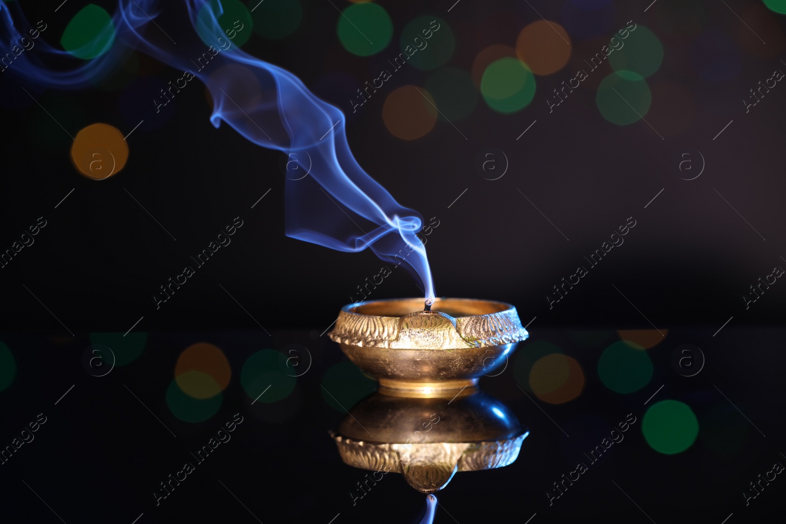 Photo of Blown out diya on dark background with blurred lights. Diwali lamp