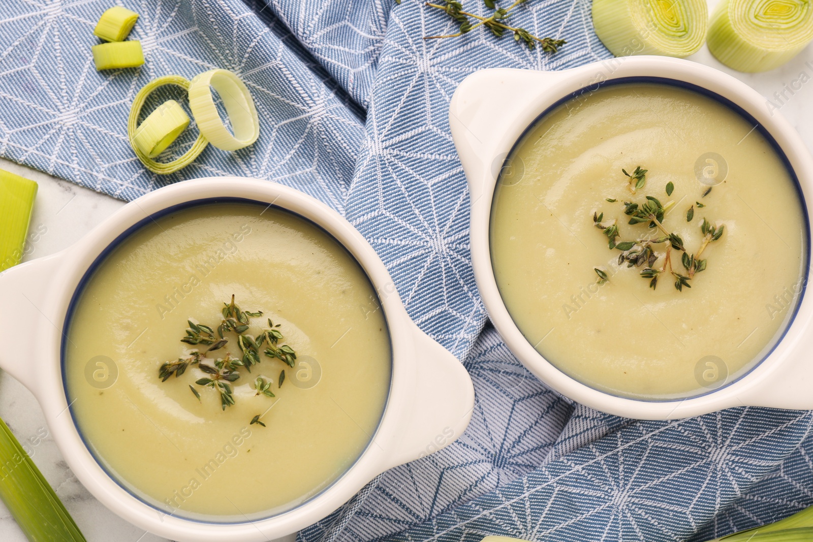 Photo of Tasty leek soup in bowls on table, flat lay