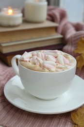 Photo of Cup of tasty hot drink with marshmallows on blanket, closeup. Autumn coziness