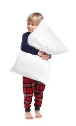 Boy in pajamas hugging pillow on white background