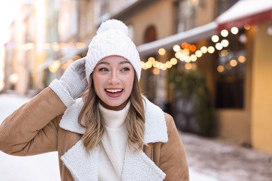 Photo of Portrait of happy woman on city street in winter. Space for text