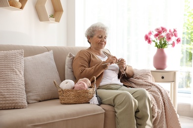 Photo of Elderly woman knitting at home. Creative hobby