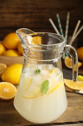 Cool freshly made lemonade in glass pitcher on wooden table