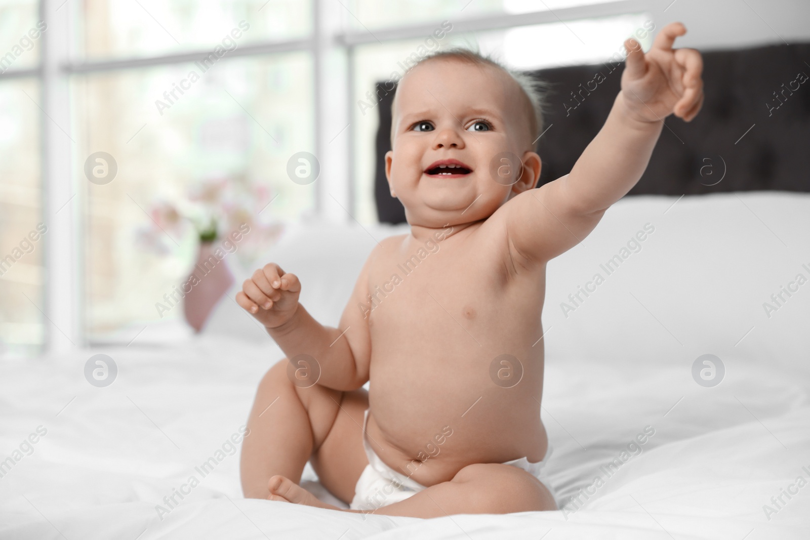 Photo of Cute baby in diaper on bed at home