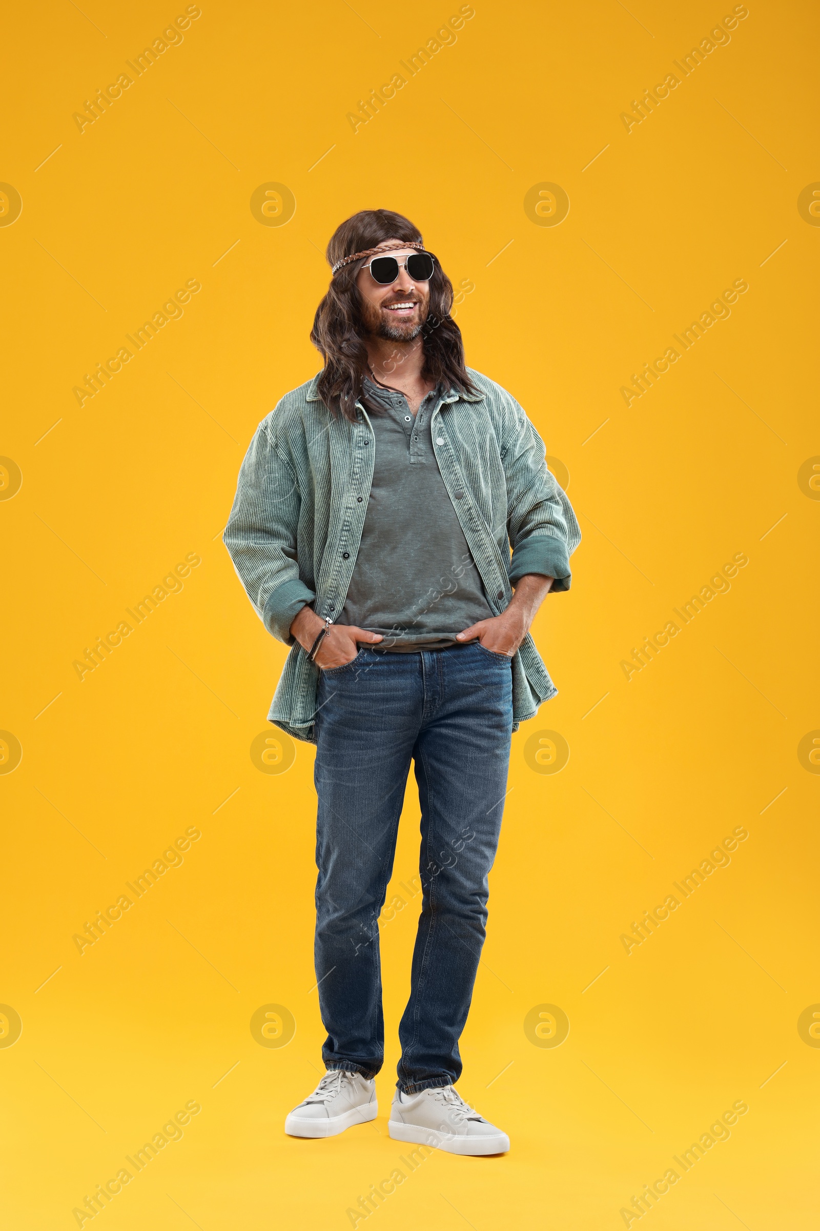 Photo of Stylish hippie man in sunglasses on orange background