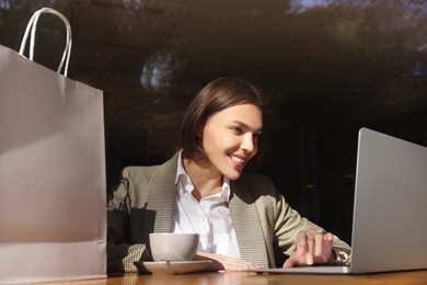 Special Promotion. Happy young woman using laptop at table in cafe