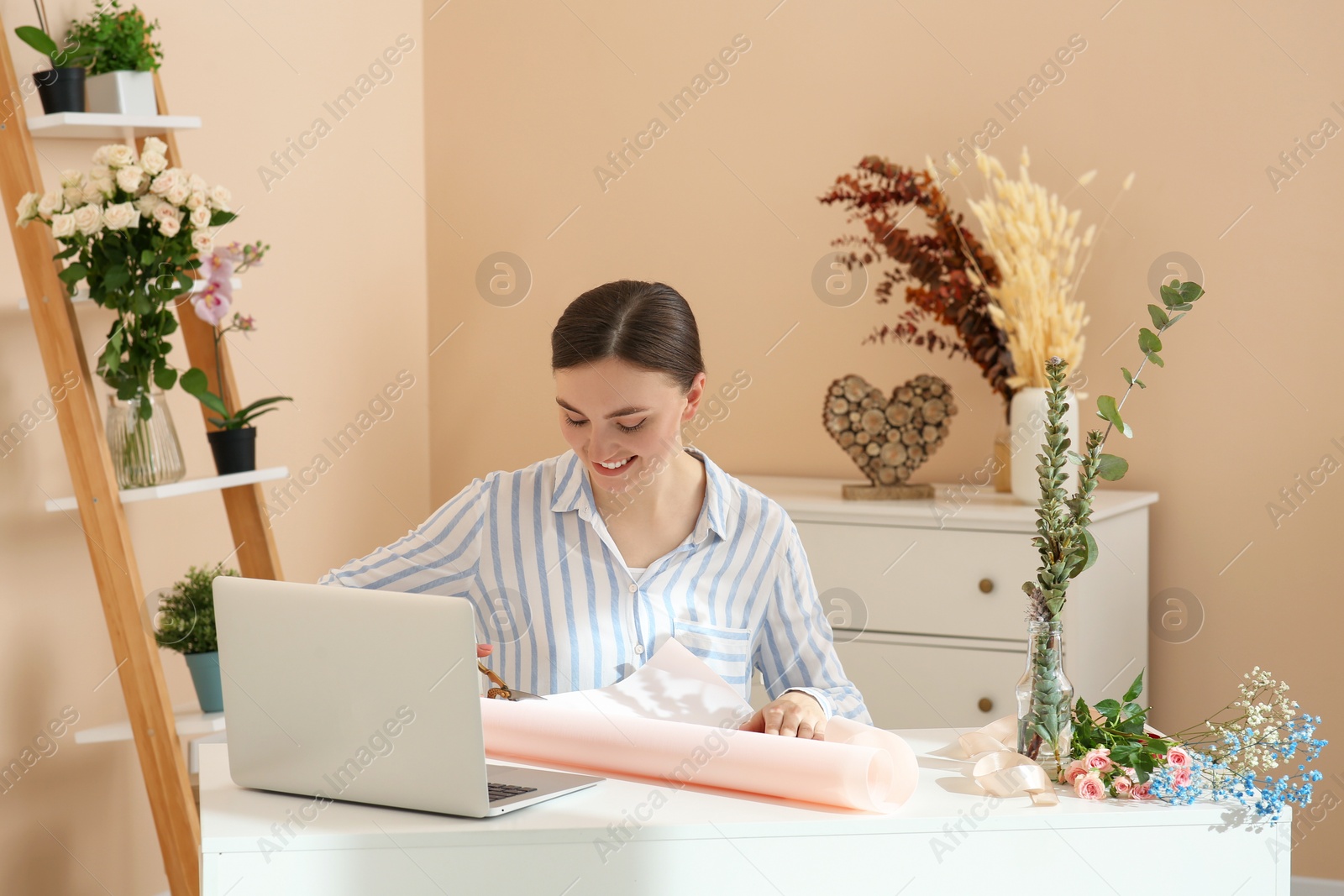 Photo of Woman making bouquet following online florist course at home. Time for hobby