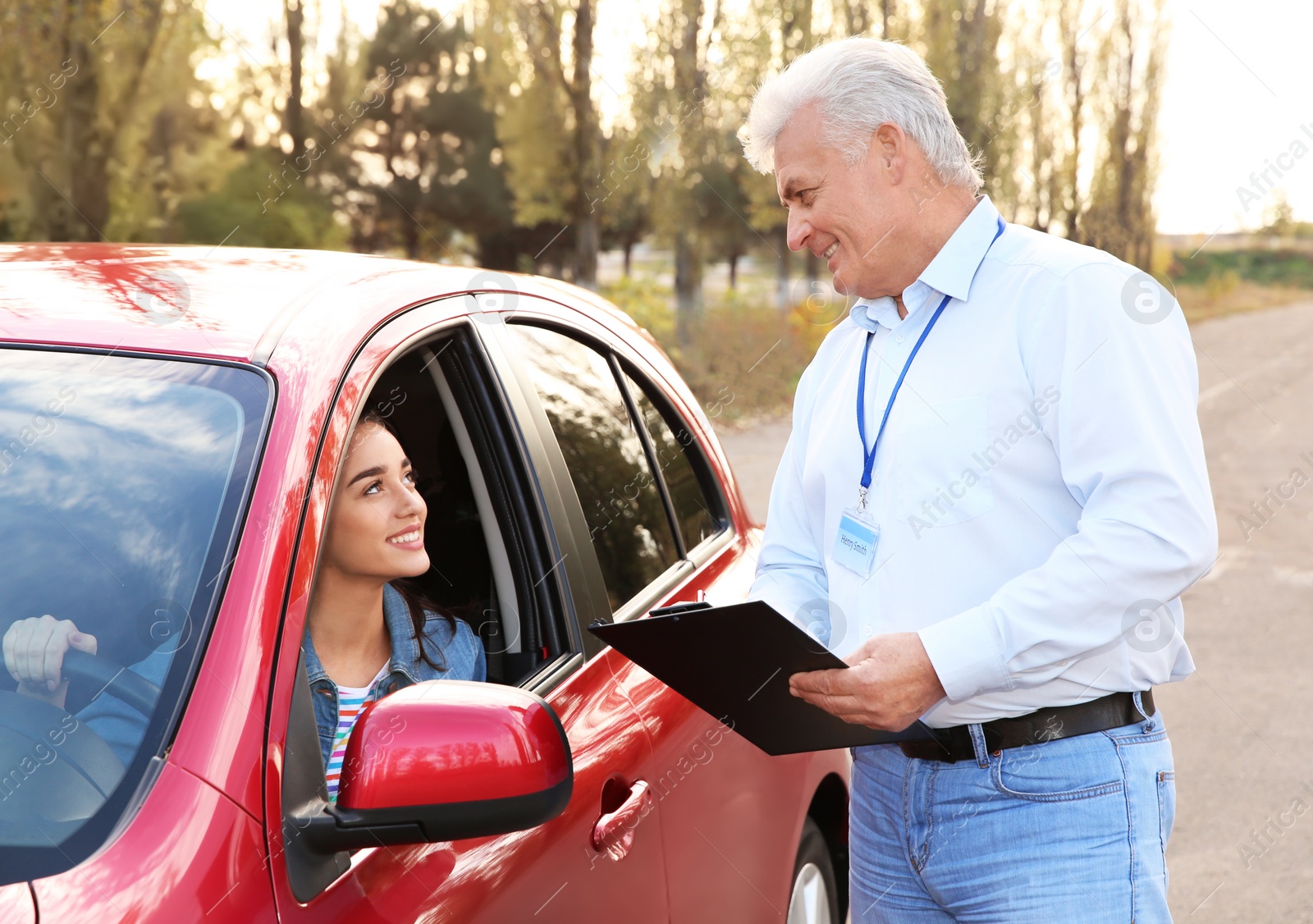 Photo of Instructor near woman in car, outdoors. Passing driving license exam